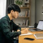 Mahasiswa belajar di meja dengan laptop, catatan, dan ponsel yang diletakkan jauh dari jangkauan